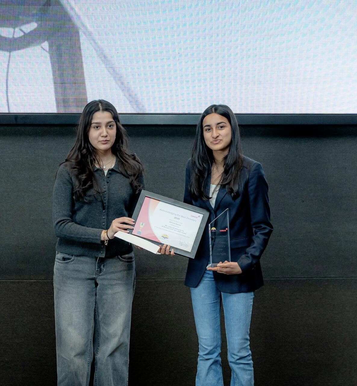 Receiving the Acknowledging the Best Debaters 2025 certificate and trophy from LUMAX