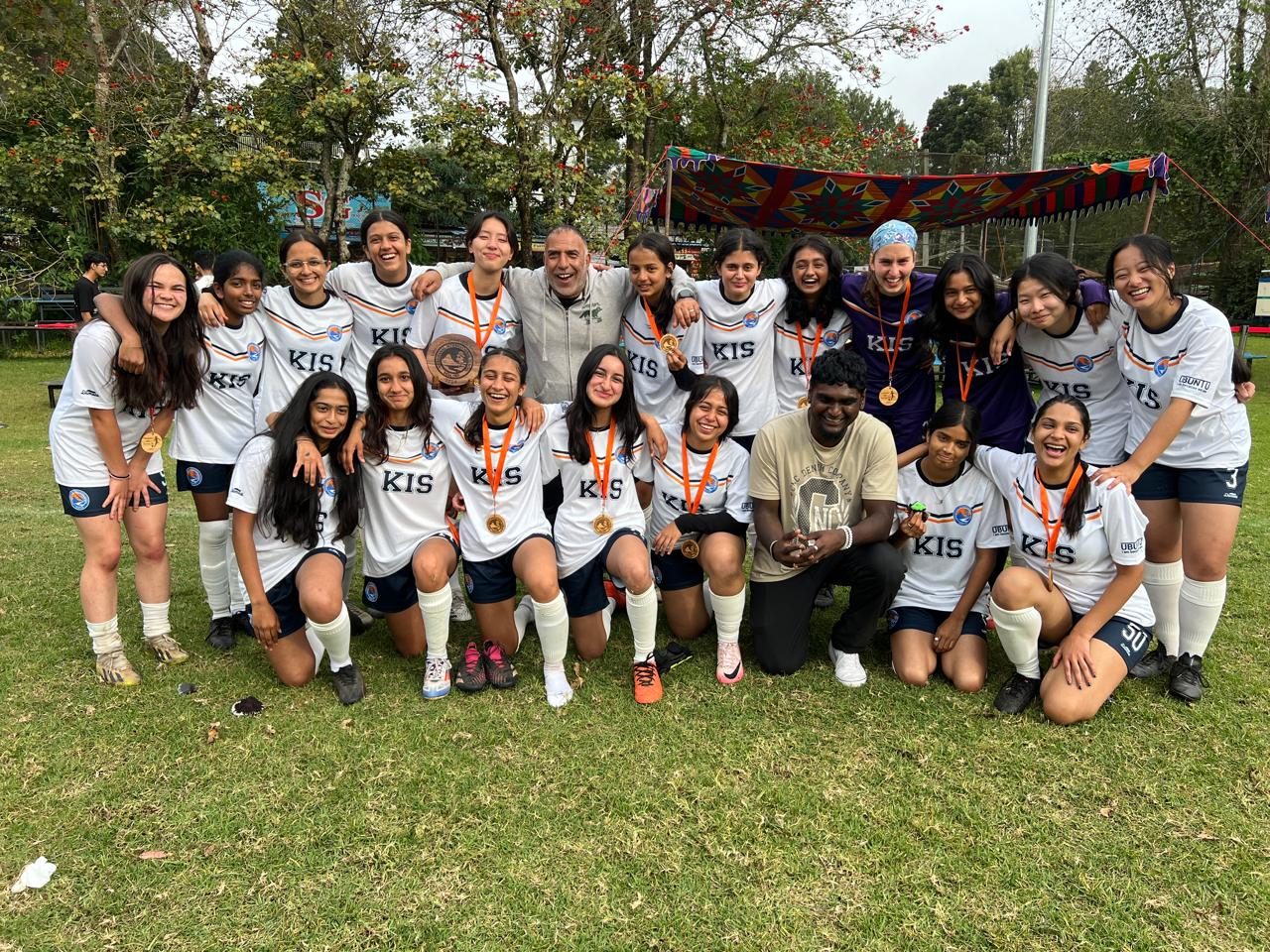 A girls' football team in white kit with medals after a match