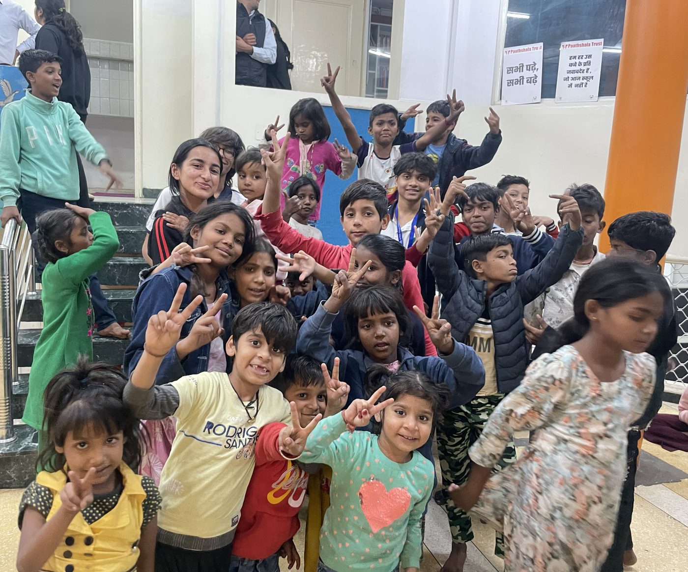 Children making peace signs with volunteers after a workshop at the Paathshala Trust