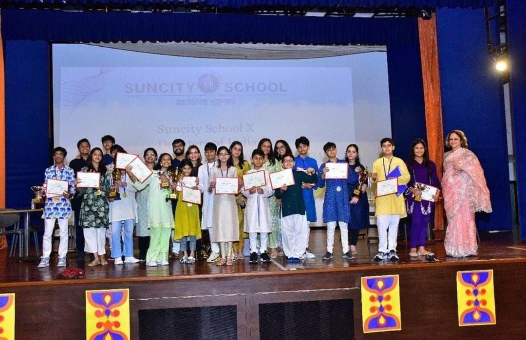 Winners holding trophies and certificates on stage at Suncity School, 2024