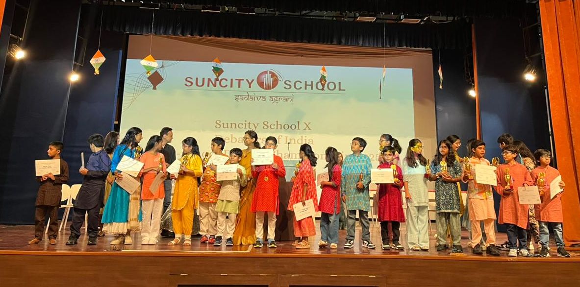 Debaters lined up on the Suncity School stage with trophies and certificates, 2025