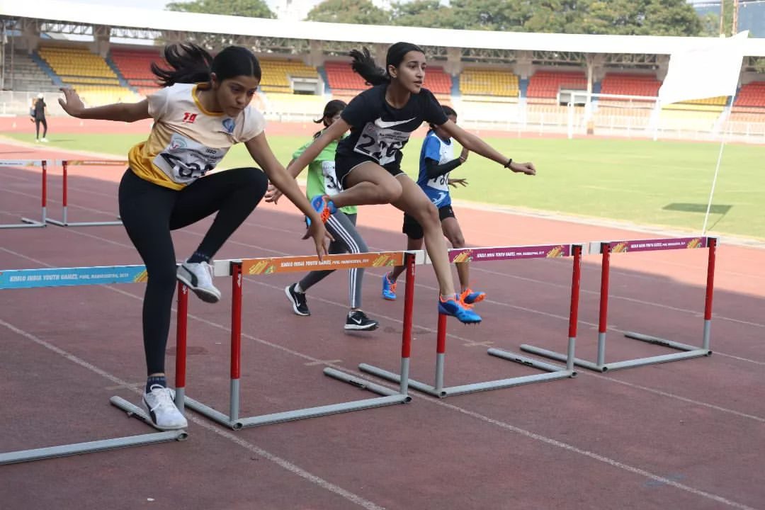 Two athletes clearing hurdles in a race