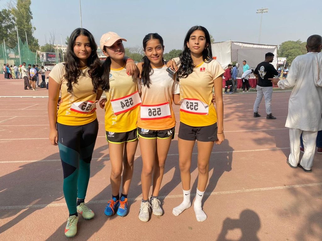 Four teammates wearing race bibs on the track